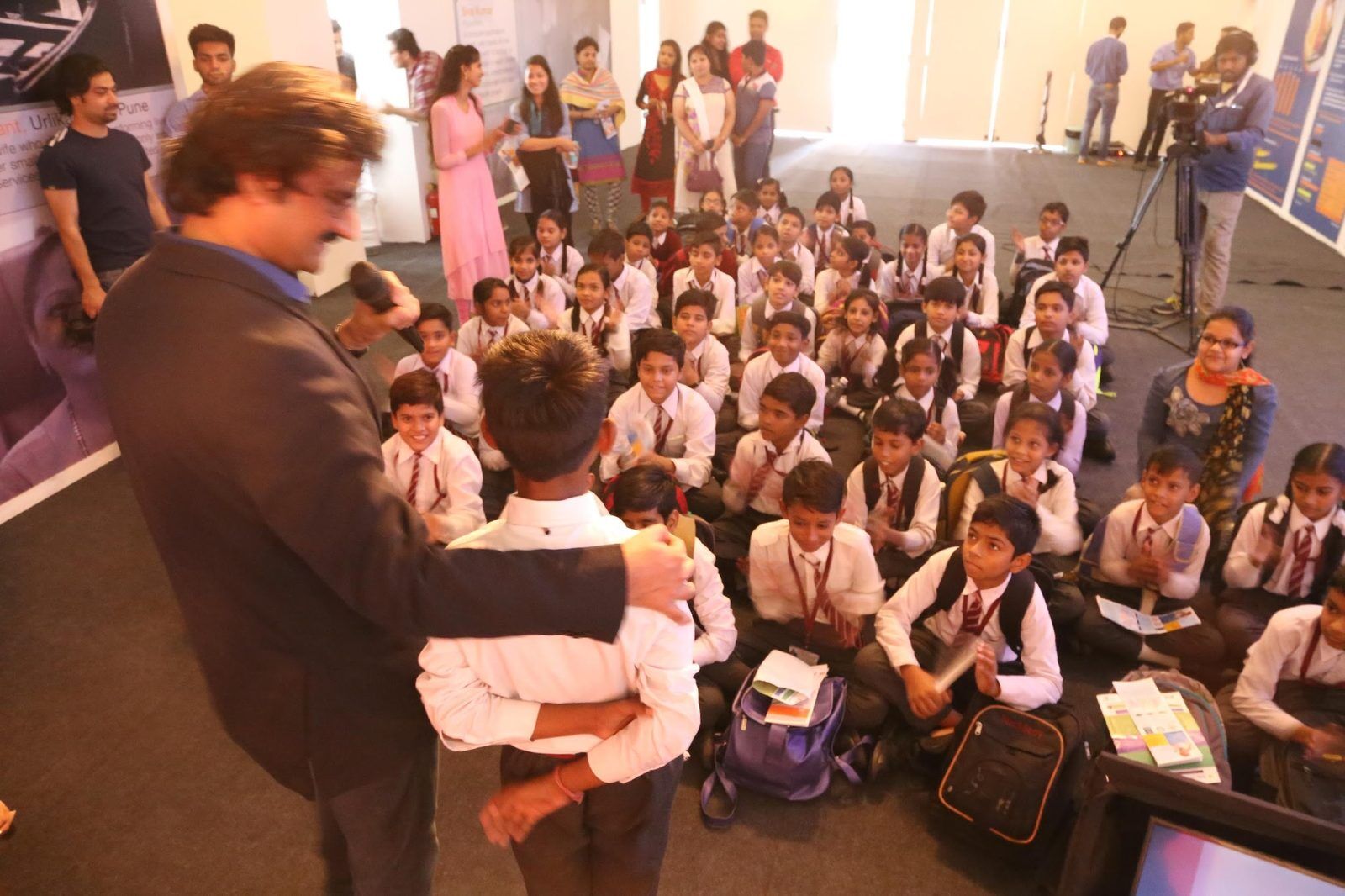Santosh Talaghatti engaging with a large group of uniformed students during a Global Classroom outreach event.